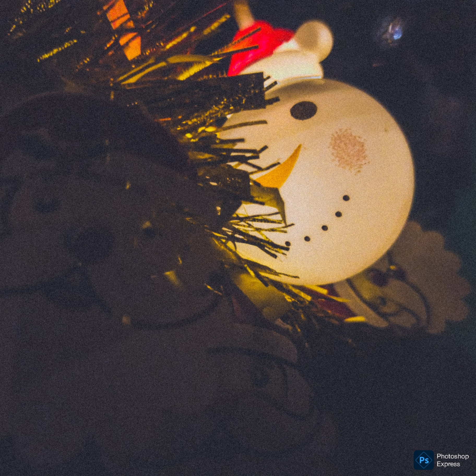 A glowing snowman decoration partially hidden by dark tree branches.