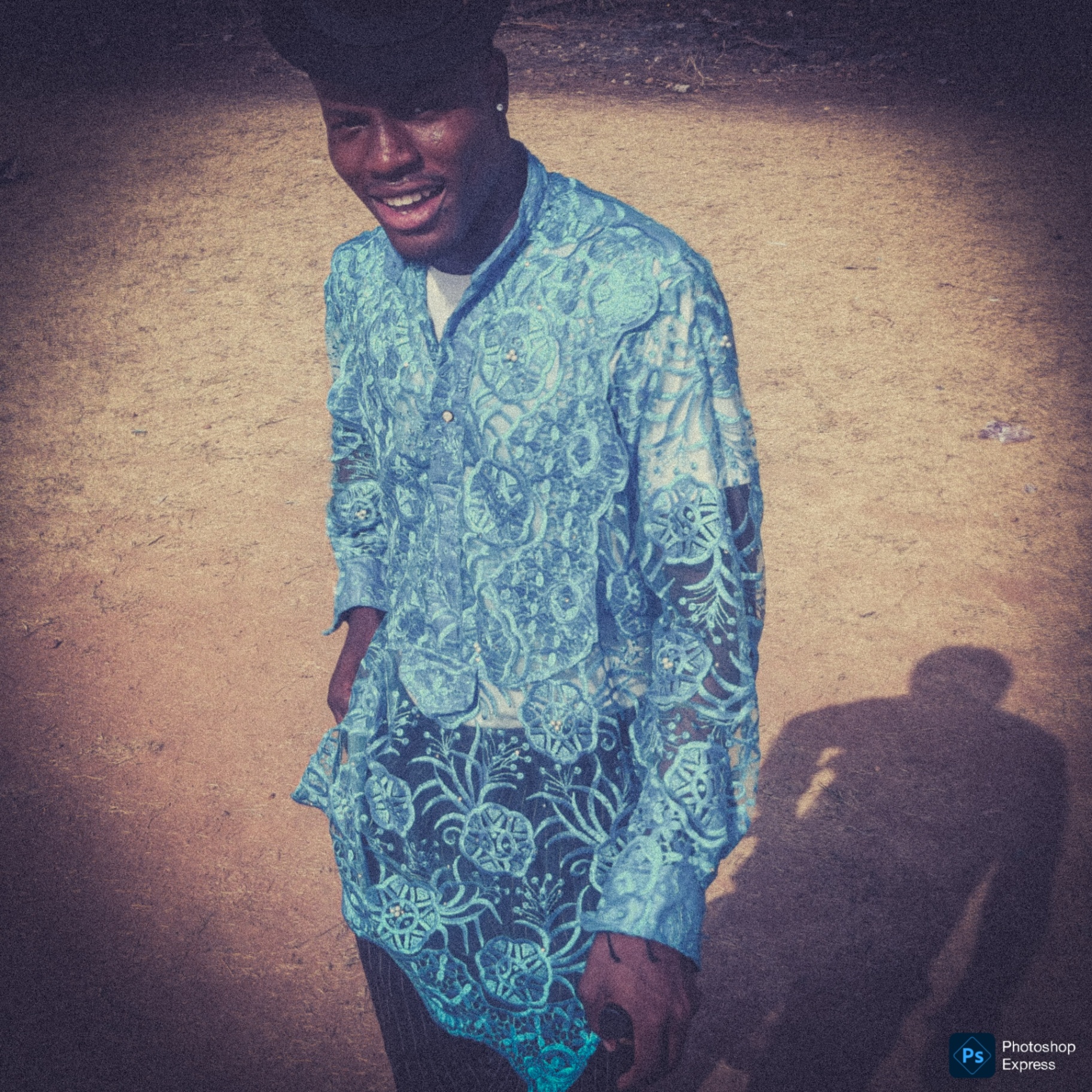 Portrait of a smiling subject in a blue patterned outfit outdoors.